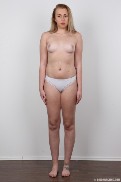 Blonde female Adela takes off her clothes while holding her face firm