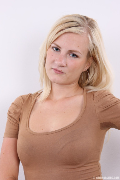 Yellow-haired young Sandra sits upon a stool after standing undressed after disrobing