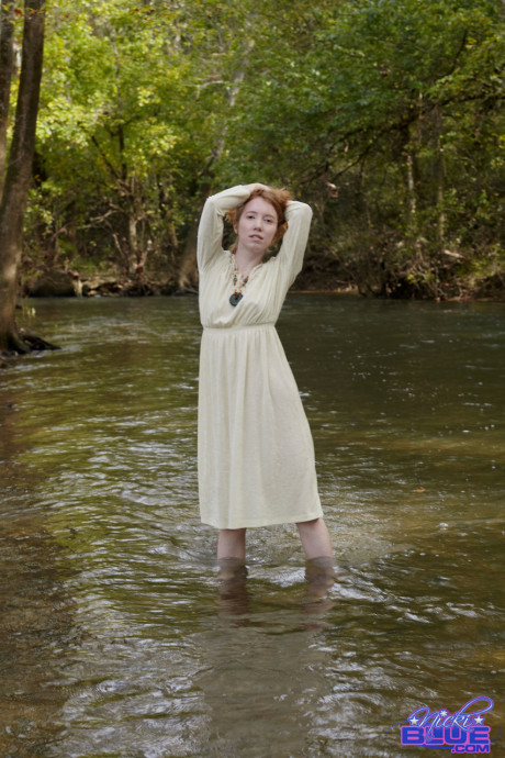 Natural ginger head Nicki Blue shows some leg while wading into a shallow stream
