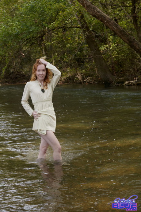 Natural ginger head Nicki Blue shows some leg while wading into a shallow stream
