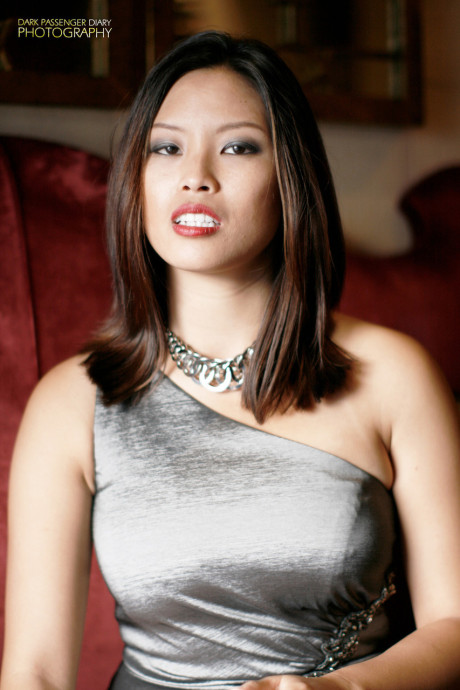 Breathtaking asian teen Zoey Jones posing in her attractive dress on the sofa