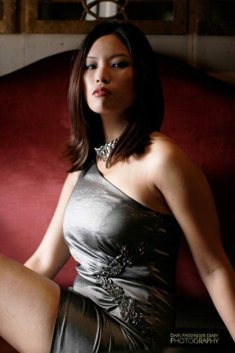 Breathtaking asian teen Zoey Jones posing in her attractive dress on the sofa