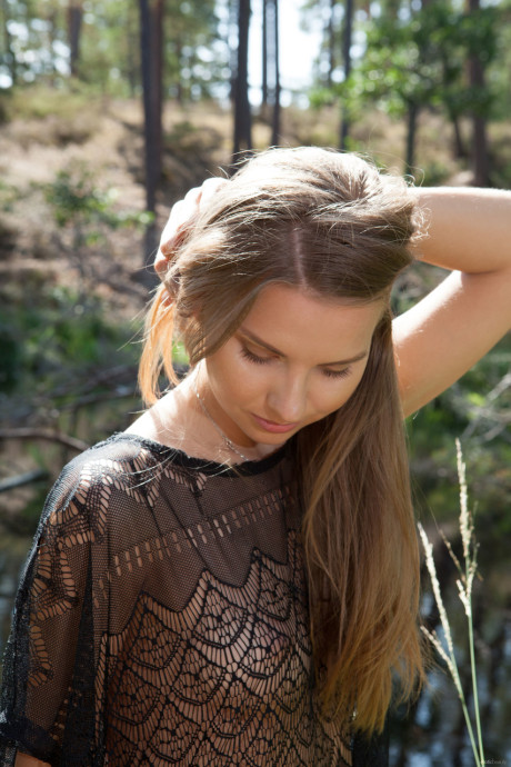 Beauty with slim body Ieva strips her sheer blouse and poses by the river