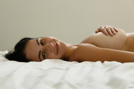 Brunette bombshell Dita Vetone teases with her gigantic melons on her bed