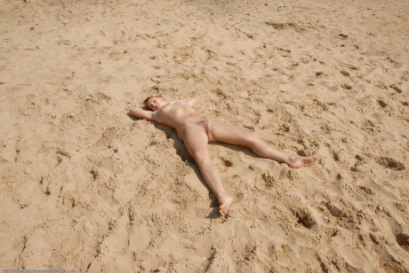 Teen Stany poses naked on a sandy beach & shows her hairy vagina up close