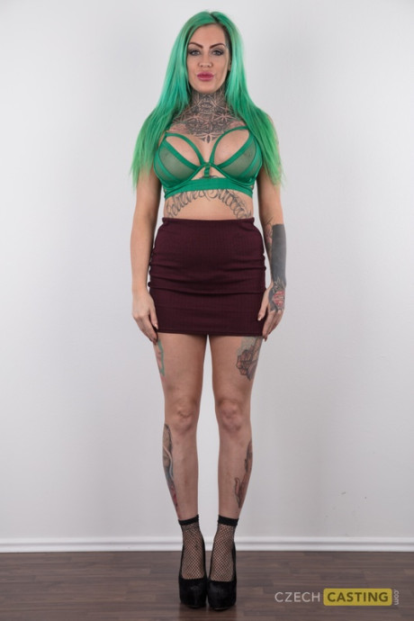 Tattooed girl gf girl with green hair and pierced nipples stands undressed after disrobing