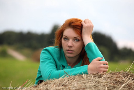 Natural redhead Amber A gets totally undressed atop a round bale of hay