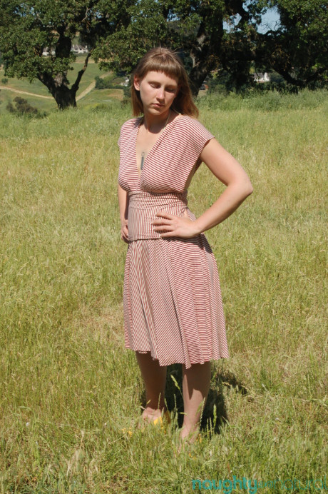 Short amateur teenie Miel undresses in a field and shows her boobies & furry twat