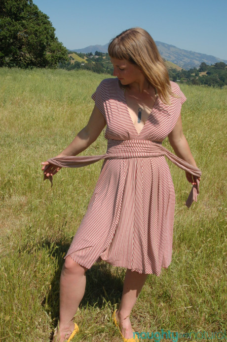 Short amateur teenie Miel undresses in a field and shows her boobies & furry twat